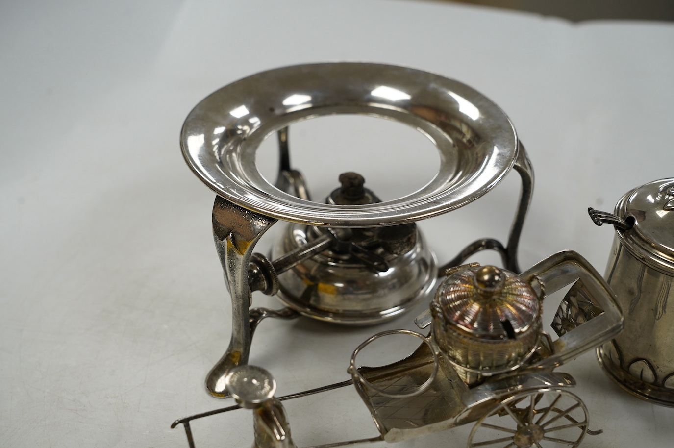Five assorted silver condiments, including Chinese white metal modelled a rickshaw, together with a plated tea kettle stand with burner. Condition - poor to fair